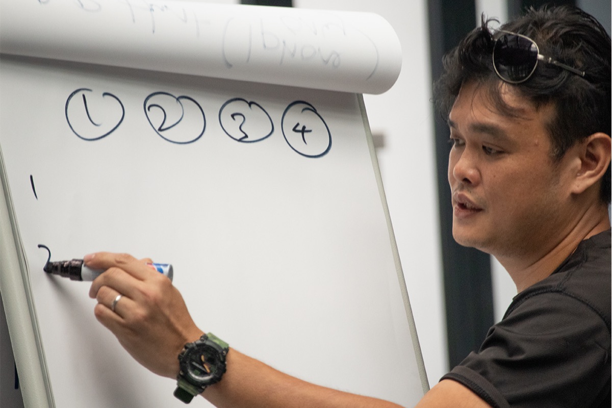 Adrian Choong reflecting beside a flipchart